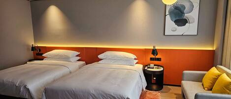 A hotel room with two beds, a sofa, a bedside table, and a wall-mounted artwork.