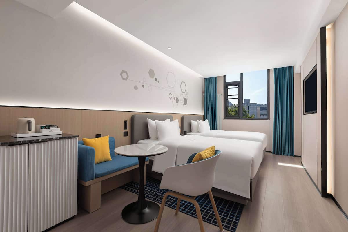 A modern hotel room with a bed, a sofa, a small table, and a chair.