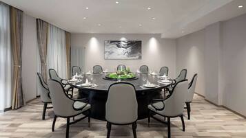 A modern conference room with a round table, grey chairs, and a central floral arrangement.