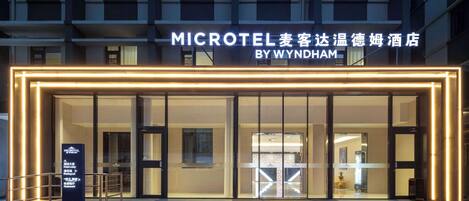A modern hotel entrance with illuminated signage and a glass facade.