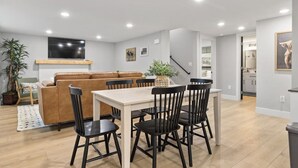 A modern living room with a sofa, dining table, and chairs, a staircase, and a kitchen area. - Steps to Hospital and MSU-B| Renovated Hospital Retreat (Billings)