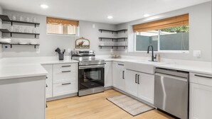 A modern kitchen with white cabinetry, stainless steel appliances, and built-in shelves. - Steps to Hospital and MSU-B| Renovated Hospital Retreat (Billings)
