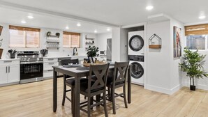 A modern kitchen with white cabinets, a built-in oven, and a dining area with a table and chairs.