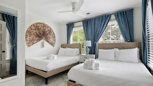 Habitación de hotel con dos camas, un ventilador de techo y un abanico decorativo grande en la pared.