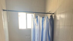 Un baño pequeño con ducha, inodoro y lavamanos.