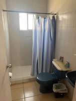 A small bathroom with a shower, toilet, and sink.