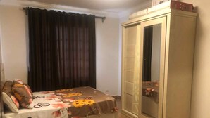 Une chambre à coucher avec un lit, une armoire, une fenêtre avec des rideaux et un petit tapis.