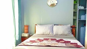 A bedroom with a bed, a clock on the wall, and a shelf with items. - Seaside Blue Inn (San Vicente)