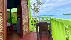 A balcony with a view of the sea and palm trees, a table, and a chair. - Seaside Blue Inn (San Vicente)