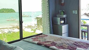 A bedroom with a large window overlooking a beach and the sea. - Seaside Blue Inn (San Vicente)