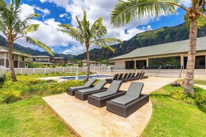 A resort with a pool area, lounge chairs, palm trees, and a mountain backdrop. - Studio Nene by AvantStay | Chic, Cozy, King Bed (Waianae)
