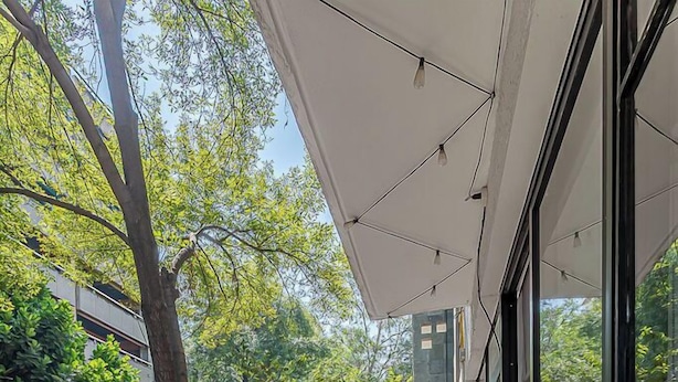 Un balcone con piante in vaso, vista sulla strada e un edificio con ampie finestre.
