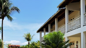 Ein Gebäude mit überdachtem Gang, Palmen und Blick auf das Meer.