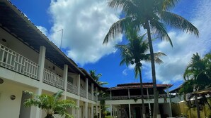Ein Hotel mit überdachtem Gang, Palmen und blauem Himmel.
