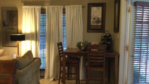 A dining area with a table, chairs, a lamp, and a window with blinds.