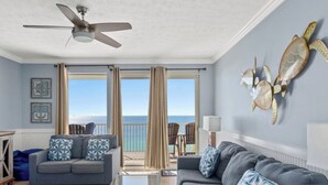 A living room with a view of the ocean, a ceiling fan, and a sofa with patterned cushions. - Beachfront PCB Rentals 1406: large balcony, owner managed, Free Beach Service! (Panama City Beach)