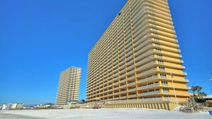 A tall, multi-story hotel with a uniform facade and balconies, situated near a beach. - Beachfront PCB Rentals 1406: large balcony, owner managed, Free Beach Service! (Panama City Beach)