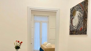 A hotel room with a bed, a white vase with flowers, a round table, and a chair. - IDEAL SUITE 41 - SALERNO AMALFI COAST POMPEI NAPLES PAESTUM (Pagani)