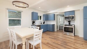 Una cocina moderna con gabinetes azules, una mesa de comedor blanca y un horno empotrado.