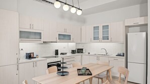 Una cocina moderna con armarios de madera clara, un lavamanos de acero inoxidable, horno empotrado, microondas y refrigerador blanco.