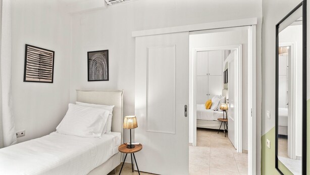 Un dormitorio moderno con una cama, una mesita de noche, una lámpara y dos obras de arte en la pared.