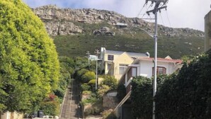 A cobblestone street with houses on one side and a rocky hillside in the background. - Havenzicht: sleep to the sound of the sea

 (Cape Town)