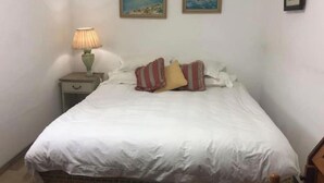 A bedroom with a bed, pillows, a nightstand with a lamp, and two framed pictures on the wall. - Havenzicht: sleep to the sound of the sea

 (Cape Town)