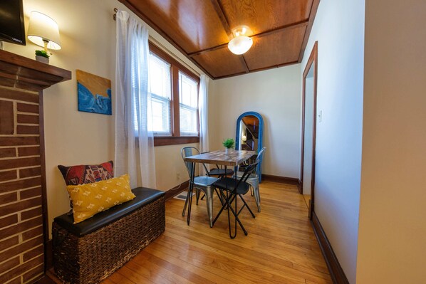 Une pièce chaleureuse avec un plafond en bois, une table à manger avec des chaises, un banc avec des coussins et une grande fenêtre avec des rideaux.