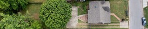 Vue aérienne d’un quartier résidentiel avec une maison, un grand arbre et une allée.