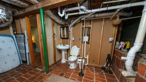 A bathroom with a toilet, sink, and visible plumbing.