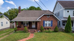 A two-story house with a front porch, a brick chimney, and a small front yard with a pathway.