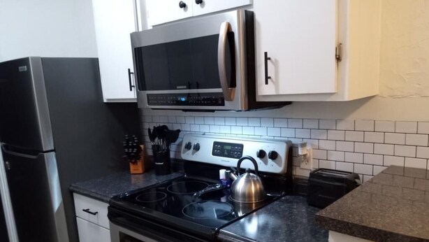 A kitchen with stainless steel appliances, including a refrigerator, microwave, stove, and oven.