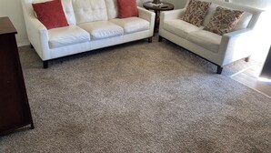 A living room with two white sofas, a small round table, and a lamp.