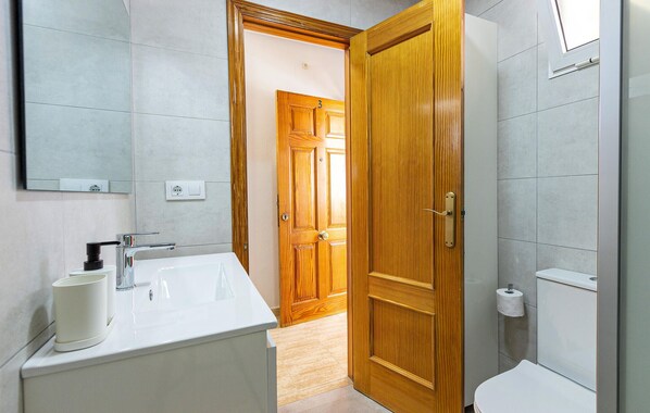 A bathroom with a white sink, a mirror, and a wooden door.