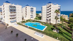 Un complexe hôtelier doté d’une piscine centrale, de nombreux balcons et offrant une vue sur la mer.
