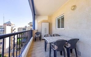 Un balcon avec une table et des chaises, une armoire et une fenêtre.