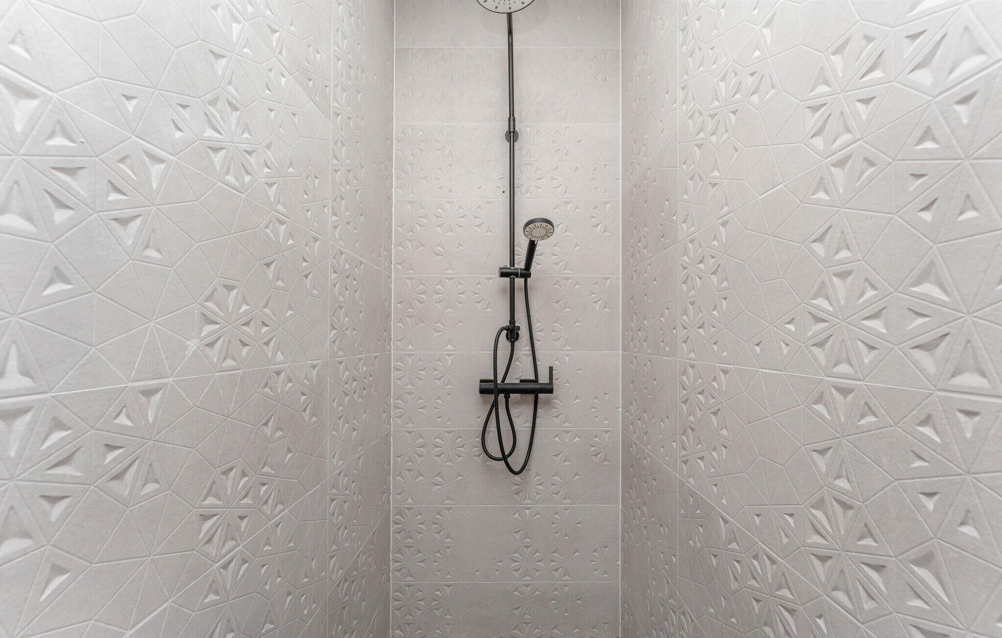 A shower with a geometric tile pattern on the walls.