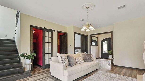 A spacious living room with a white sofa, a patterned rug, and a staircase leading to another level. - Lovely studio with AC in charming College Station (College Station)