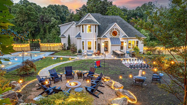 Una casa de dos pisos con un patio que tiene mobiliario exterior y una chimenea.