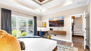 Un dormitorio con una cama grande, un escritorio, un televisor y vistas al exterior.