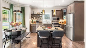Una cocina moderna con una isla central, taburetes de bar y una mesa de comedor para dos personas.