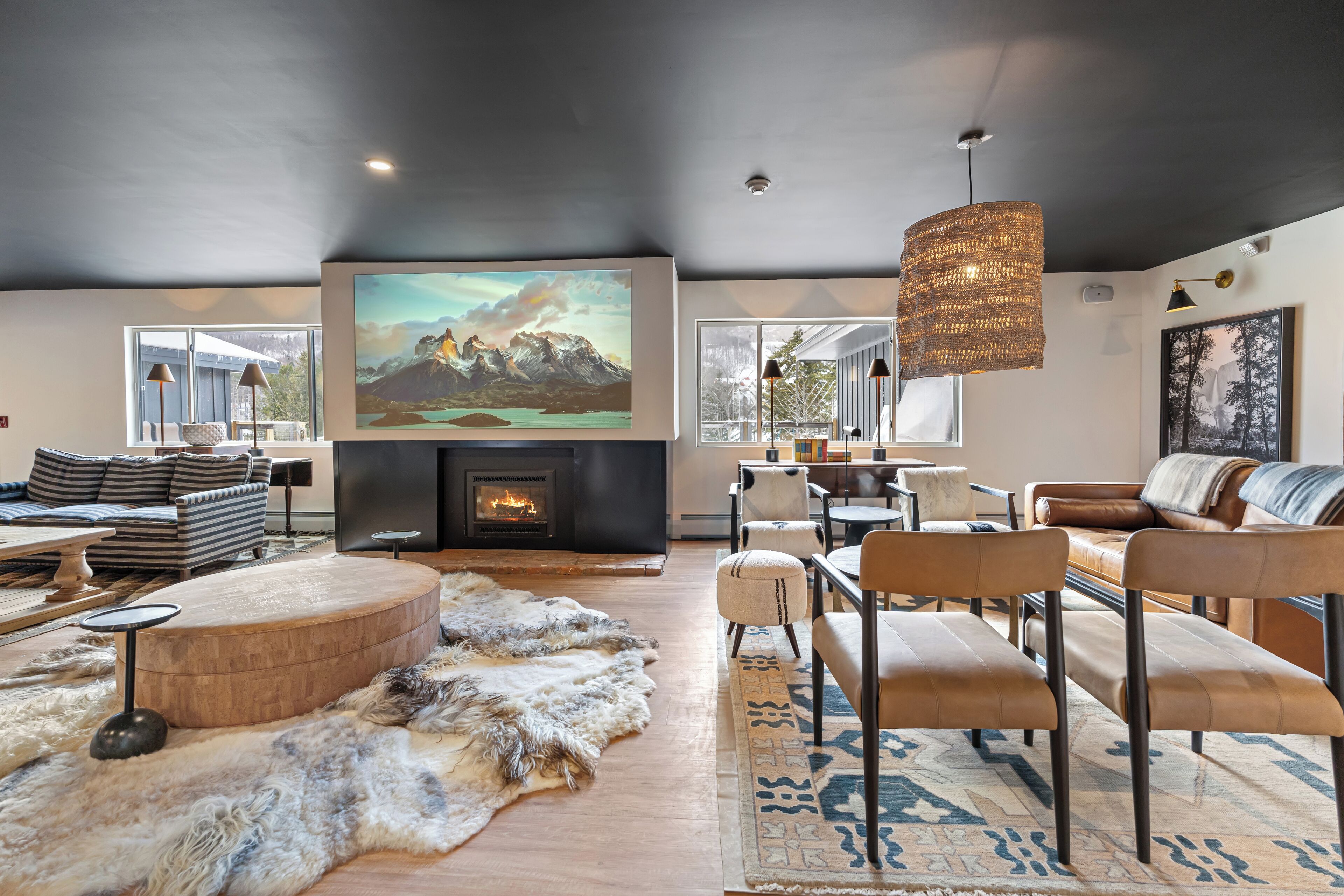 A spacious living room with a fireplace, comfortable seating, and large windows.