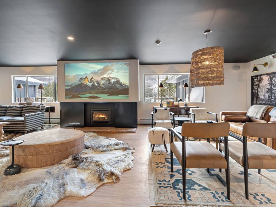 A spacious living room with a fireplace, comfortable seating, and large windows.