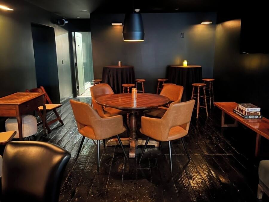 A cozy restaurant with a wooden table and chairs, dark walls, and a wooden floor.