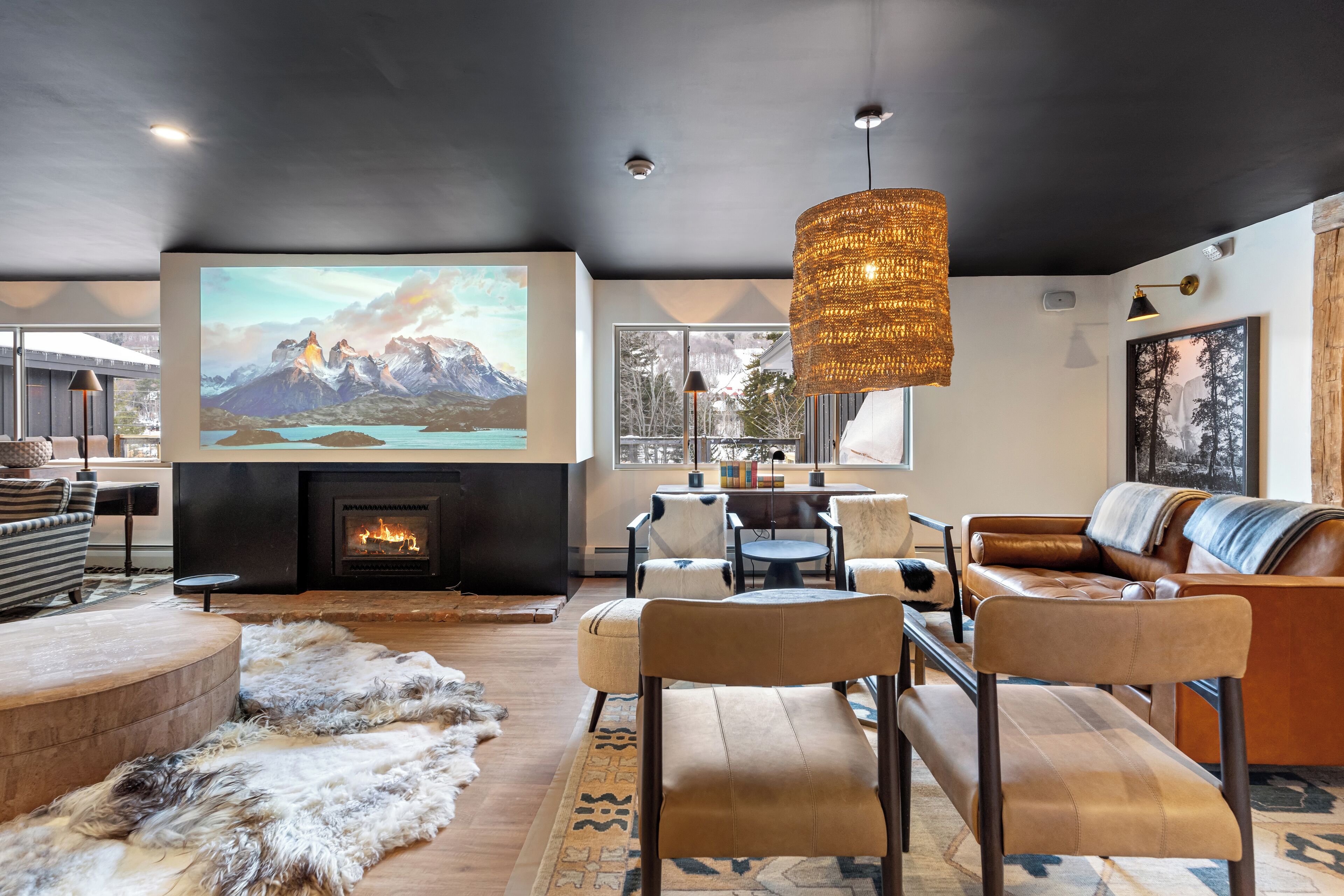 Un salon moderne doté d’une cheminée, de sièges confortables et d’un grand écran diffusant un paysage de montagne.