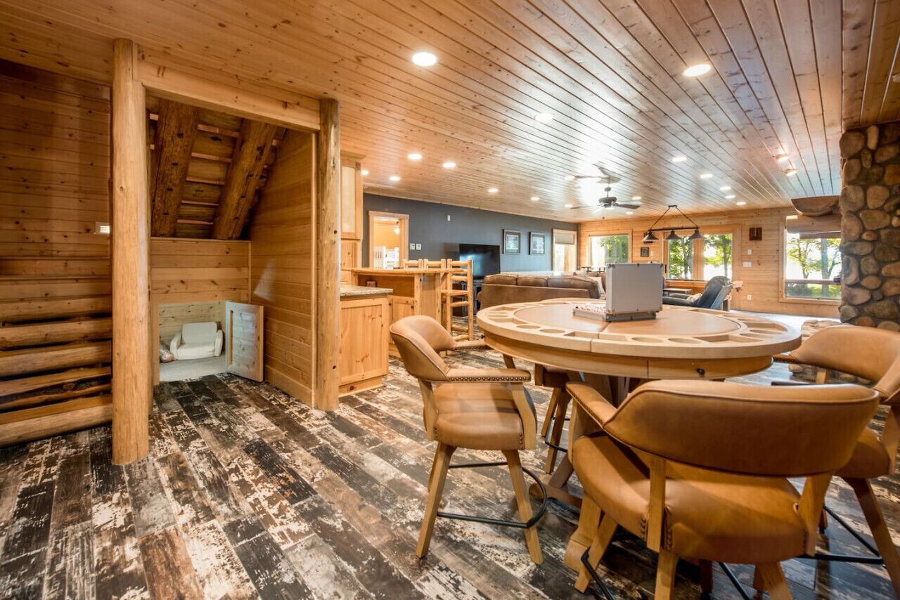 L’intérieur chaleureux d’un chalet en bois comprend une table et des chaises en bois, un coin cuisine et une cheminée en pierre.