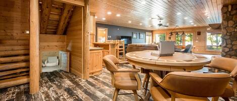 L’intérieur chaleureux d’un chalet en bois comprend une table et des chaises en bois, un coin cuisine et une cheminée en pierre.