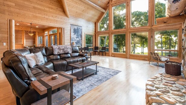 A spacious living area with a large leather sofa, a coffee table, and a stone fireplace.