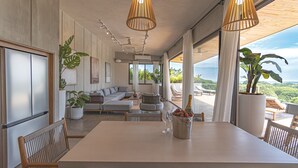 A spacious dining area with a large table, chairs, and a bottle of champagne. There are potted plants and a view of the outdoors. - Blanco Mar Ocean view (Cóbano)