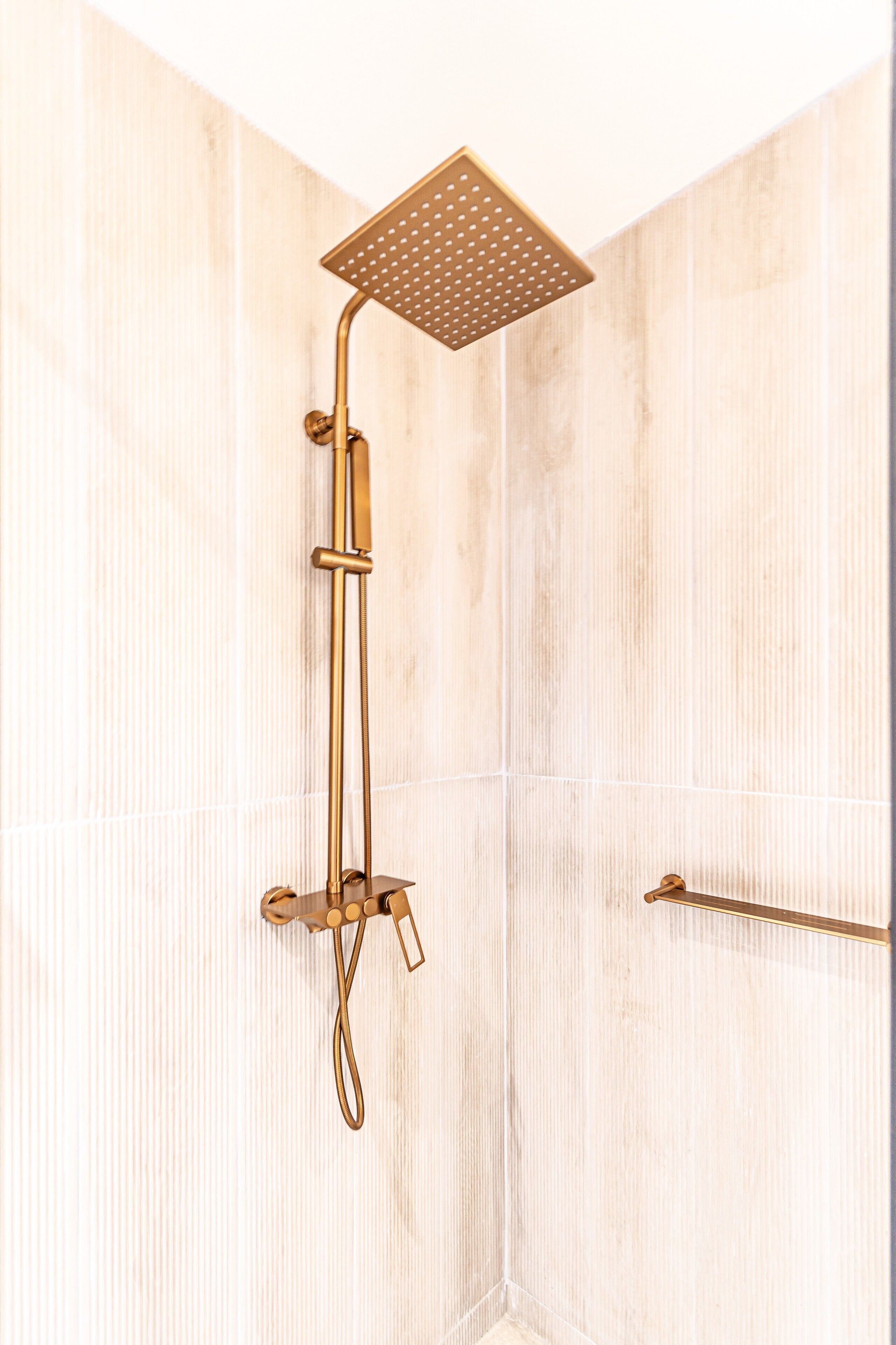 Une douche avec un pommeau de douche carré et un pommeau de douche à main.